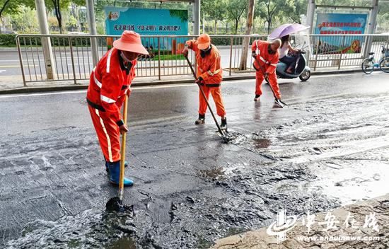  环卫工人清理道路上堆积的淤泥