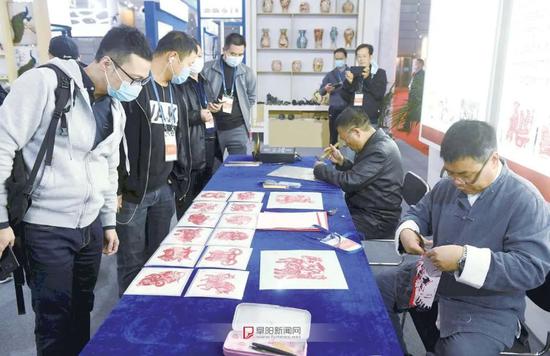(阜阳剪纸展位前,围满感兴趣的参观者)