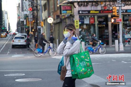 当地时间3月21日,美国纽约时代广场一位行人防护严密。中新社记者 廖攀 摄