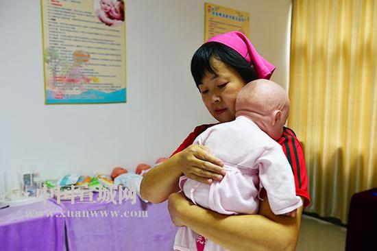 一位月嫂在演示如何正确搂抱婴儿。