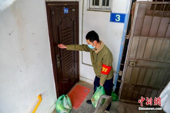 2月10日，武汉市江汉区新华街取水楼社区为辖区的老人送菜上门，社区工作人员把菜放在门口，敲门提醒老人菜已送到。 中新社记者 张畅 摄