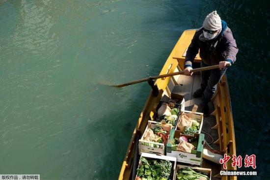 　当地时间3月25日，意大利威尼斯，一名男子划船为水城的居民提供日常蔬菜水果。