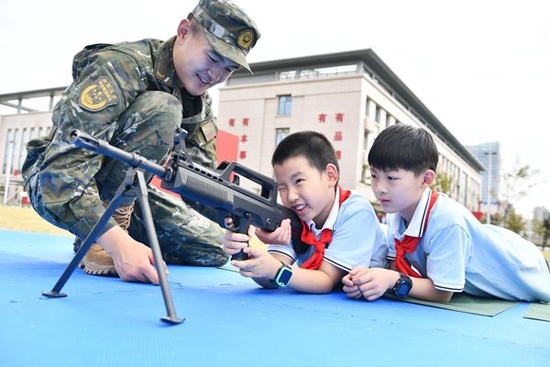 小学生在武警官兵的指导下操作武器装备。