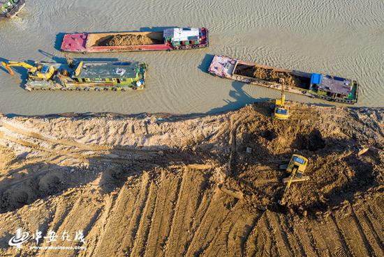 庐江县庐城镇境内的罗埠河水毁工程修复施工现场,大型机械在船只的配合下紧张施工