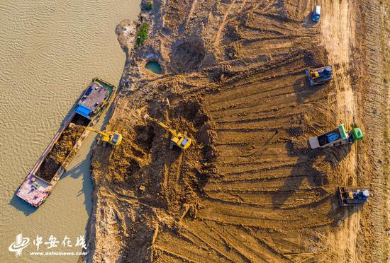 庐江县庐城镇境内的罗埠河水毁工程修复施工现场，大型机械在船只的配合下紧张施工