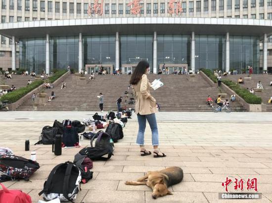 不少考生为抢占图书馆作为，用书包等站队。图为一名大学生在图书馆门前排队、背书。 韩章云 摄