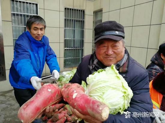 韩友谊（左一）为环卫工人发放大白菜