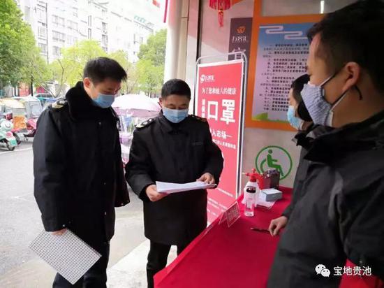 图为胡勇芳(左二)在农贸市场防控点检查