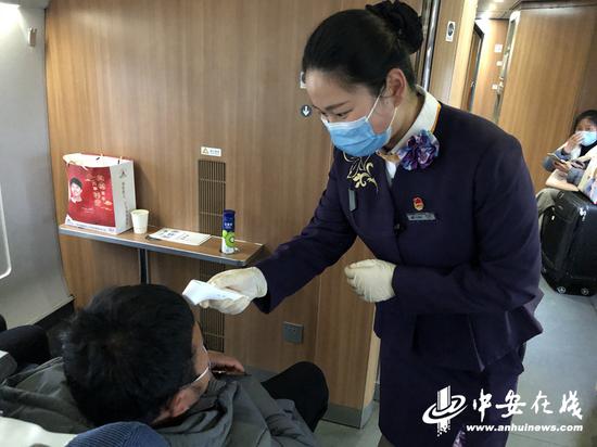 　　2月27日，g7795次列车乘务人员为务工旅客测量体温。 刘娟萍 摄