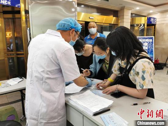 5月15日晚，在合肥市安徽国际旅行卫生保健中心新冠疫苗免费接种点，工作人员为市民解答注意事项。　储玮玮 摄