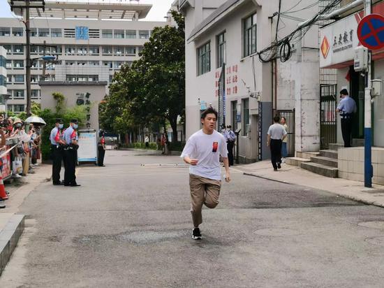在合肥六中南区考点,伴随着考试结束的铃声,一个考生奔跑出考场,两边的家长为他鼓掌呐喊加油。
