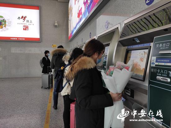 旅客在黄山北站自动售取票机前取票。(陆杨摄)