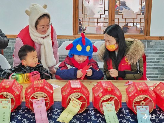2024年2月2日,志愿者在安徽省合肥市肥东县众兴乡先锋农场指导小朋友剪窗花。