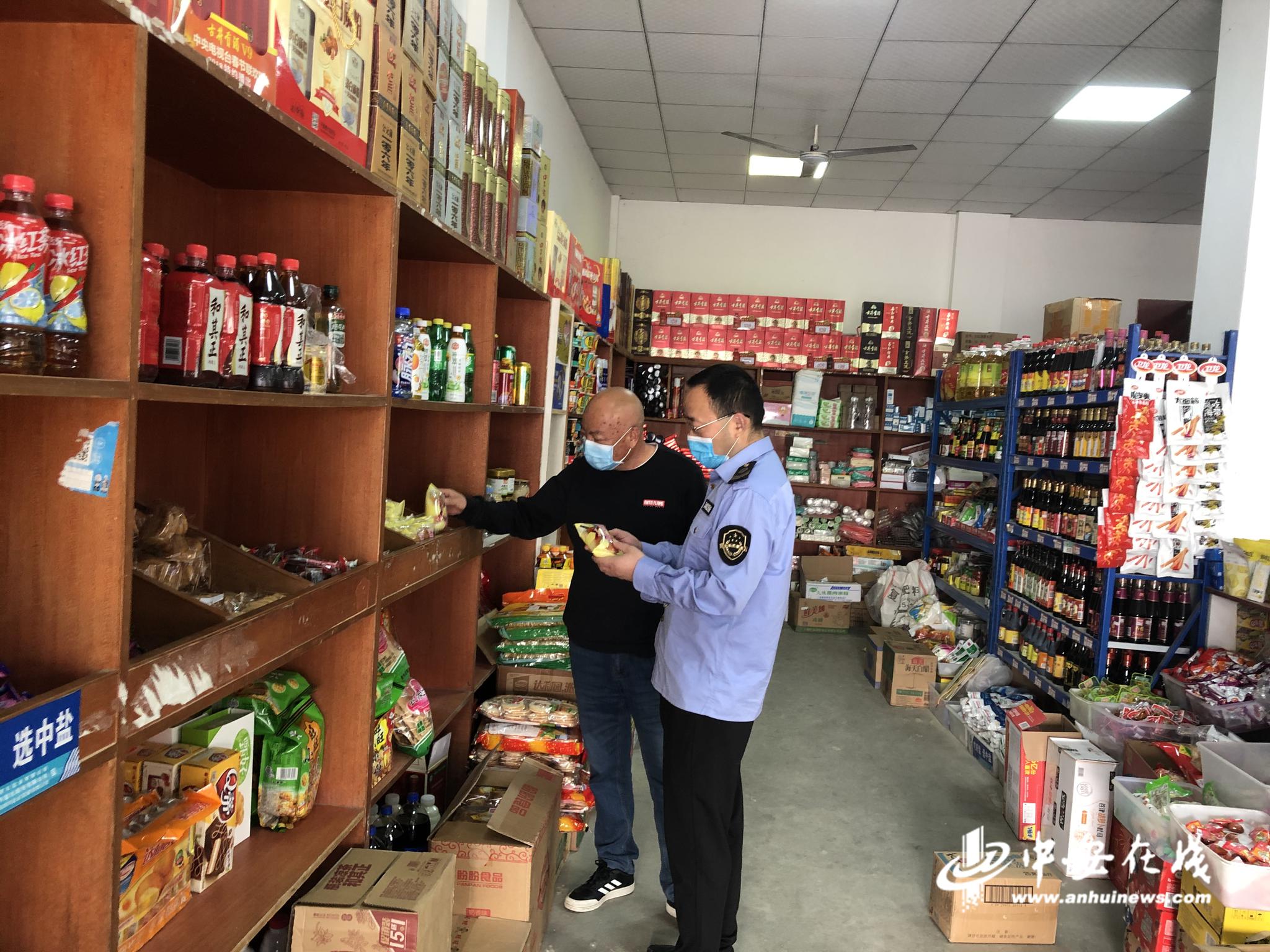 图为执法人员正在检查超市食品安全