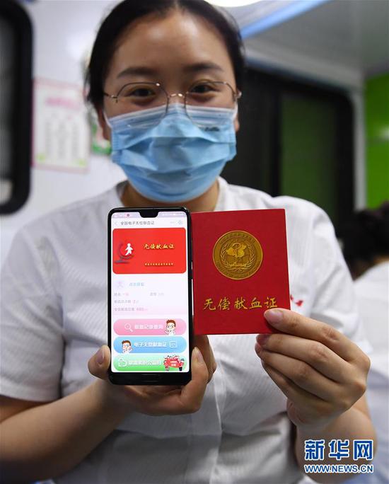 6月14日，在贵州省仁怀市的一处爱心献血屋，工作人员展示手机里的电子无偿献血证（左）。新华社发（陈勇 摄）