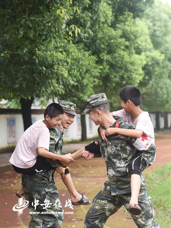 2020年7月21日，安徽铜陵，在安徽省铜陵市义安区太平中心小学防汛安置点，武警合肥支队医疗小分队卫生员陪一对留守双胞胎男孩做游戏。