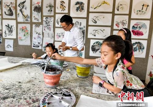 7月5日，新疆乌鲁木齐，一家培训机构的暑期国画班里，孩子们正在做绘画前的准备工作。中新社记者 刘新 摄