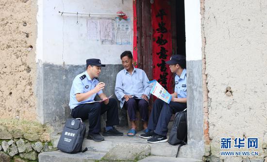 庐镇派出所干警上门向村民宣传法律知识（摄于8月21日）。新华网发（王可海 摄）