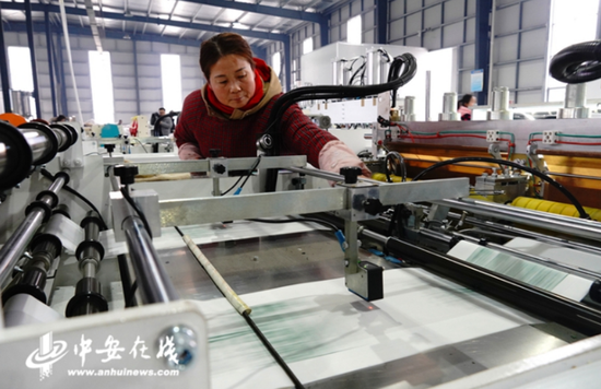 在桐城市双新产业园,一名工人正在操作机器,生产可降解的塑料袋