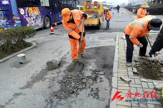 市政工人修补金寨路非机动车道的坑洞