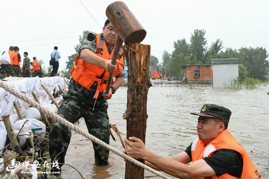 王彬在堤坝水中抡锤打桩