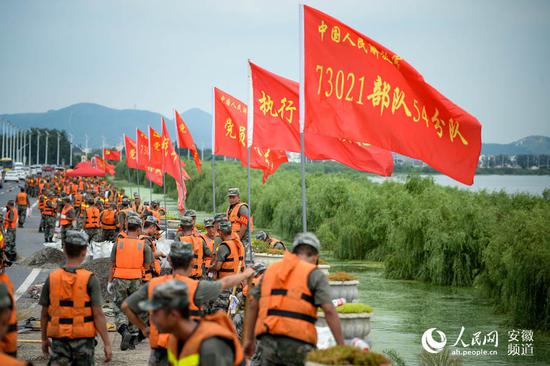 部队官兵装填沙袋，加高加固环巢湖大道长临河段。苗子健摄