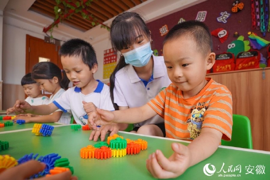 在老师的带领下,孩子们玩着益智玩具。