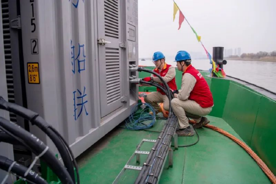 供电员工在江心洲码头电动货船上检查电池和充电设备