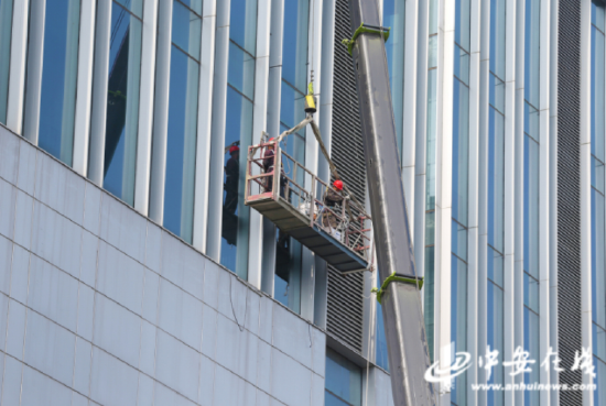  城市“蜘蛛人”正在高楼玻璃幕墙上进行亮化