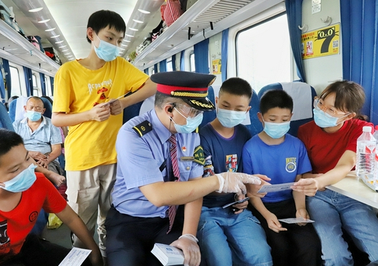 杭州客运段列车乘务员向学生旅客发放乘车防疫提示卡，宣传防疫知识。 周围 摄