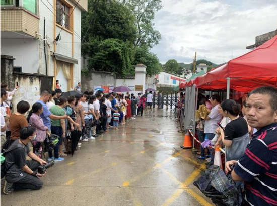 图为考试即将结束,歙县中学考场外,家长冒雨等候。
