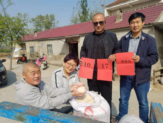 杨苏祥(左一)帮助贫困户销售自产大米