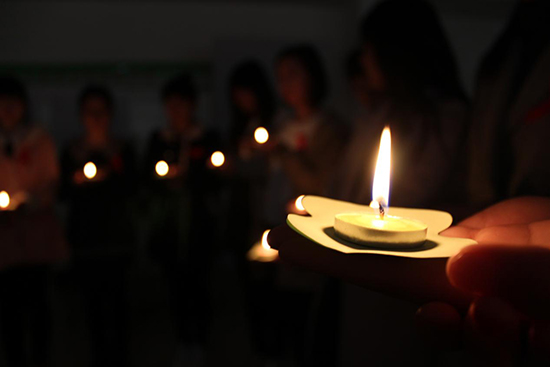 每位志愿者佩戴红丝带手捧蜡烛进行祈福