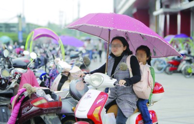 市民骑行装有遮雨棚的电瓶车
