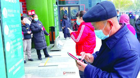 商场门口研究手机的老人
