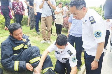↑救护人员正在为一位消防人员的脚部伤势进行处理。
