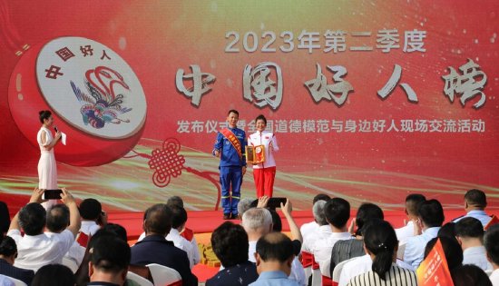 全国道德模范提名奖获得者於若飞向敬业奉献“中国好人”代表徐梦桃赠送“道德传家宝”。高晟寒 摄