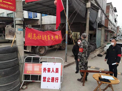 (桂健为来往的人员测量体温)