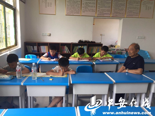 图为杨靖澜老师在义务辅导孩子们做作业