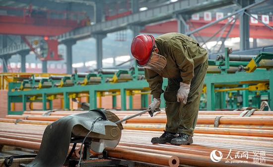 铜管生产车间里工人正在切割原材料。人民网 王锐摄