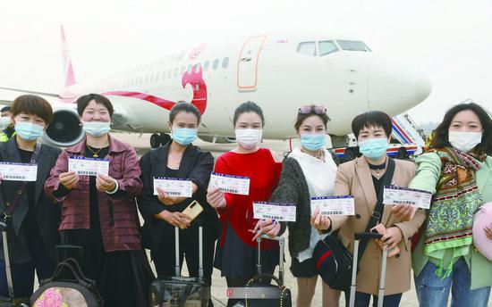 27日上午,旅客展示手中的登机牌,她们准备乘坐新开通的哈尔滨阜阳三亚航班。
