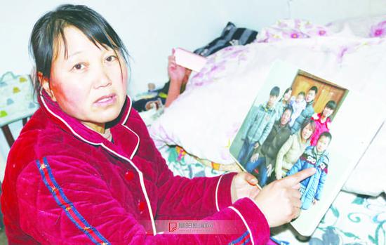 小豪的妈妈看着生病前儿子的照片,期盼儿子早日恢复健康
