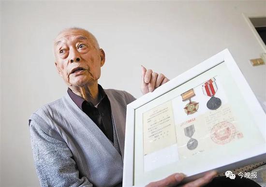 老战士张申手拿军功章向记者讲述曾经的峥嵘岁月。