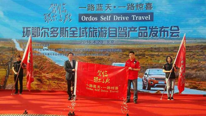 现场授启动大旗;左一:鄂尔多斯市副市长李国俭;右一:李鹏 爱车环球自驾汽车文化(集团)俱乐部执行会长