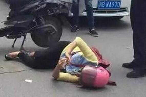 女子出车祸被刮倒 躺地玩手机影响交通