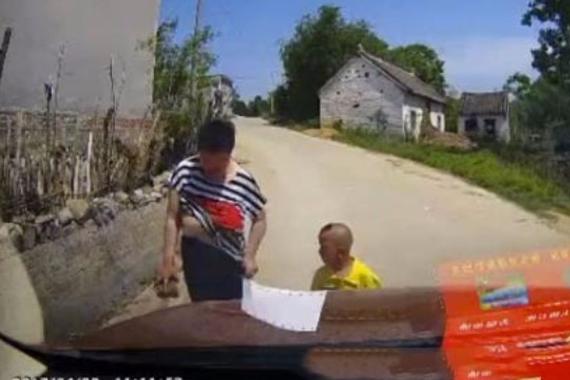 妇女带着小孩拦车要钱 拿着砖头脱衣