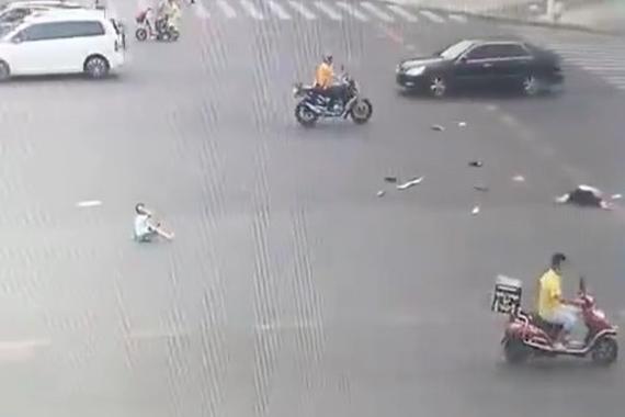 电动车女子疑似闯红灯被撞飞，后座小孩摔倒在地