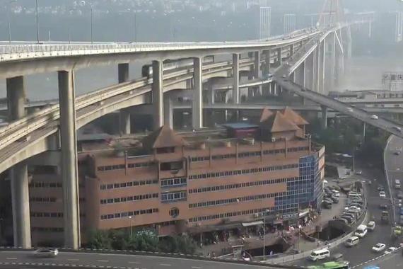 居民楼顶上开轻轨，轻轨头上有汽车