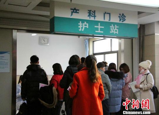 图为孕妇在家属的陪同下,在产科门诊前排队测量血压。 赵晓 摄