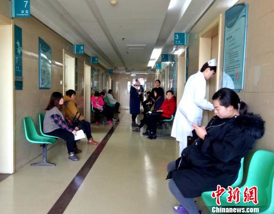 图为在山东大学第二医院产科门诊楼内,孕妇们在走廊里等待被“喊号”,做身体检查。 赵晓 摄